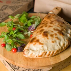A delicious calzone sits on a wooden board.