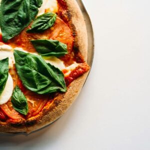 pizza with green leaves on white ceramic plate