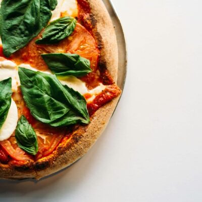pizza with green leaves on white ceramic plate